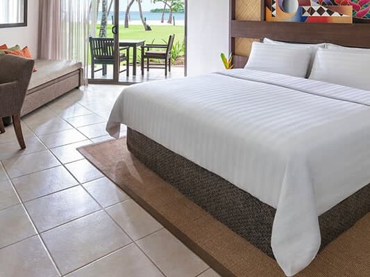 Refurbished resort guest room in Fiji with upholstered bed, timber joinery and garden doors